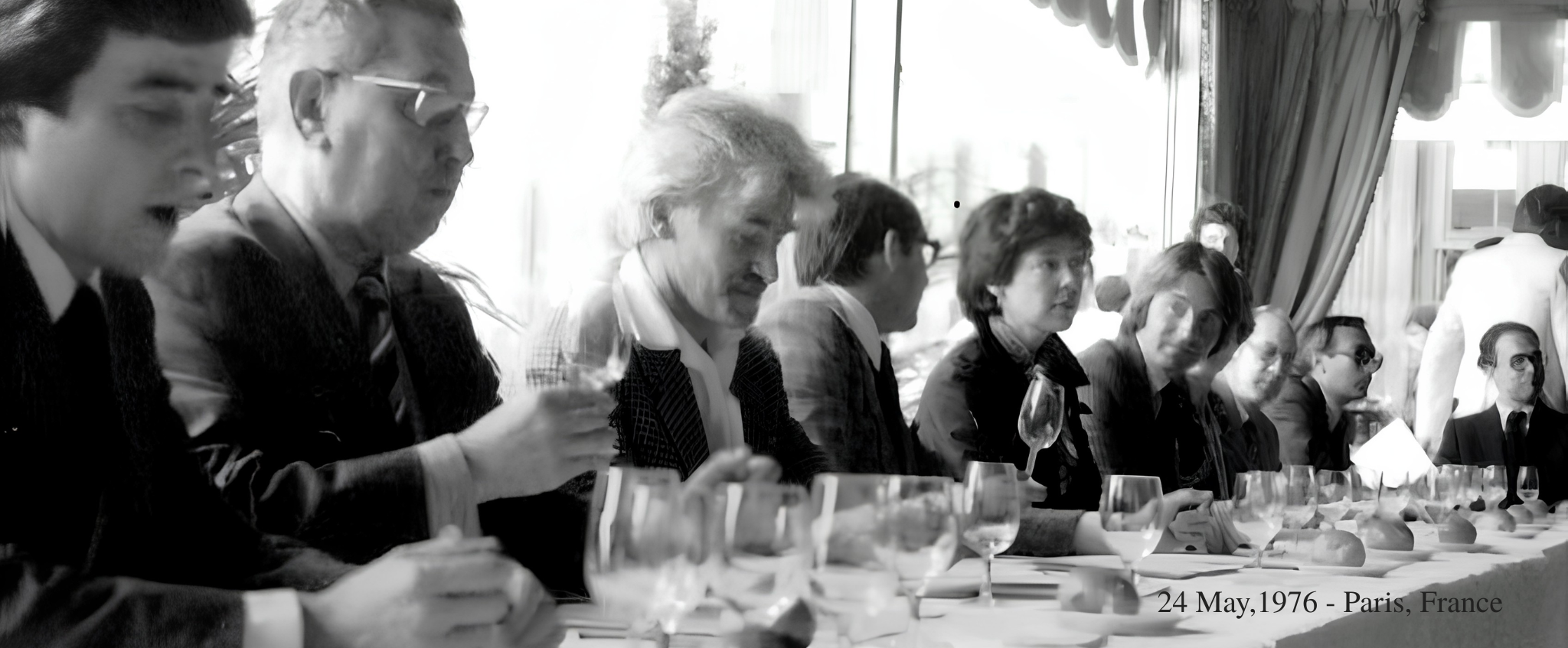 Black and white photograph taken on 24 May 1976 in Paris, showing a panel of judges seated along a long table covered with wine glasses, tasting and evaluating wines at the original Judgement of Paris.